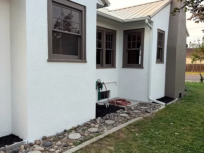 Finished stucco home exterior with new windows and landscaping