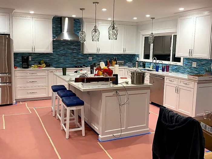 Completed kitchen remodel with white cabinetry and a glass tile backsplash